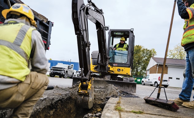 A John Deere 50P Tier Compact Excavator is effortlessly digging a trench with its bucket