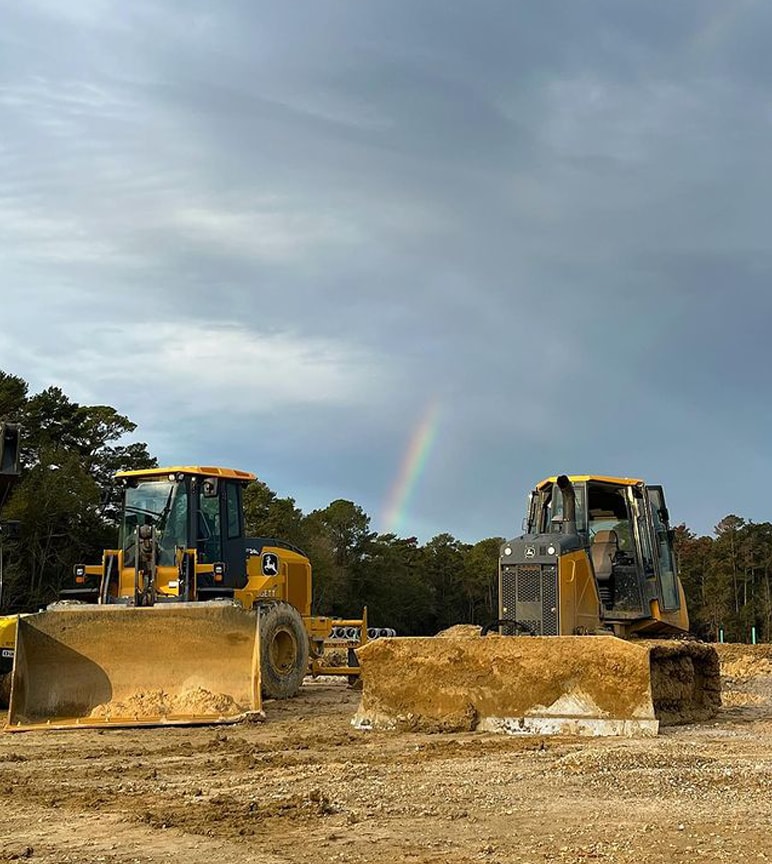 John Deere dozer and wheel loader in front of a rainbow.