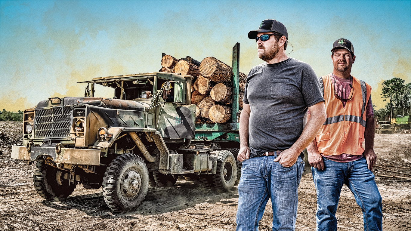 Ron and Rusty Delk of R&R Swamp Logging stand at a landing site with a logging truck behind them.