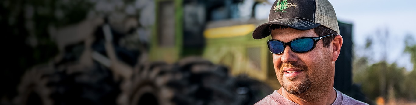 Owner Rusty Delk looking to the left with an 848L II Grapple Skidder behind him.