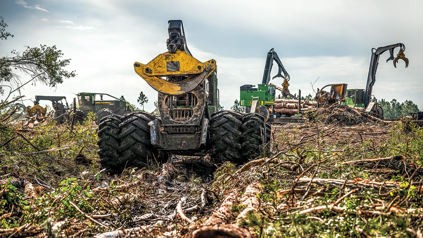 From left to right. A John Deere 848L-II, 948L-II Grapple Skidders with two 437E Knuckleboom Loaders work together at the landing.