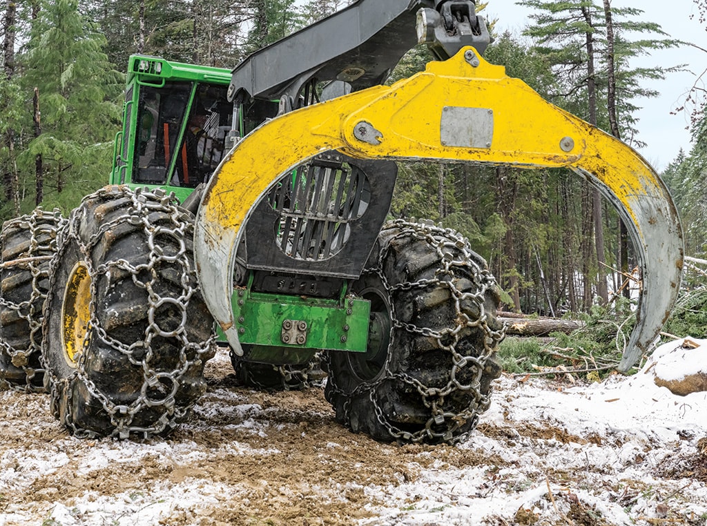 Front view of the 848L-II skidder with chains on the tires and wide-open grapple.