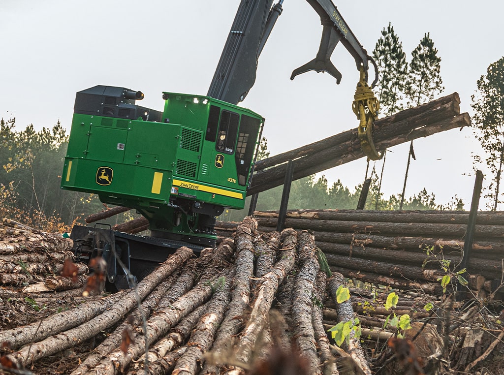 The 437E Knuckleboom Loader collects and stacks felled trees onto a trailer to be transported from the logging site.