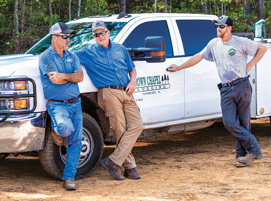 Randy chats with Bud while Matt stands at the closed door of his dad’s company pickup truck.