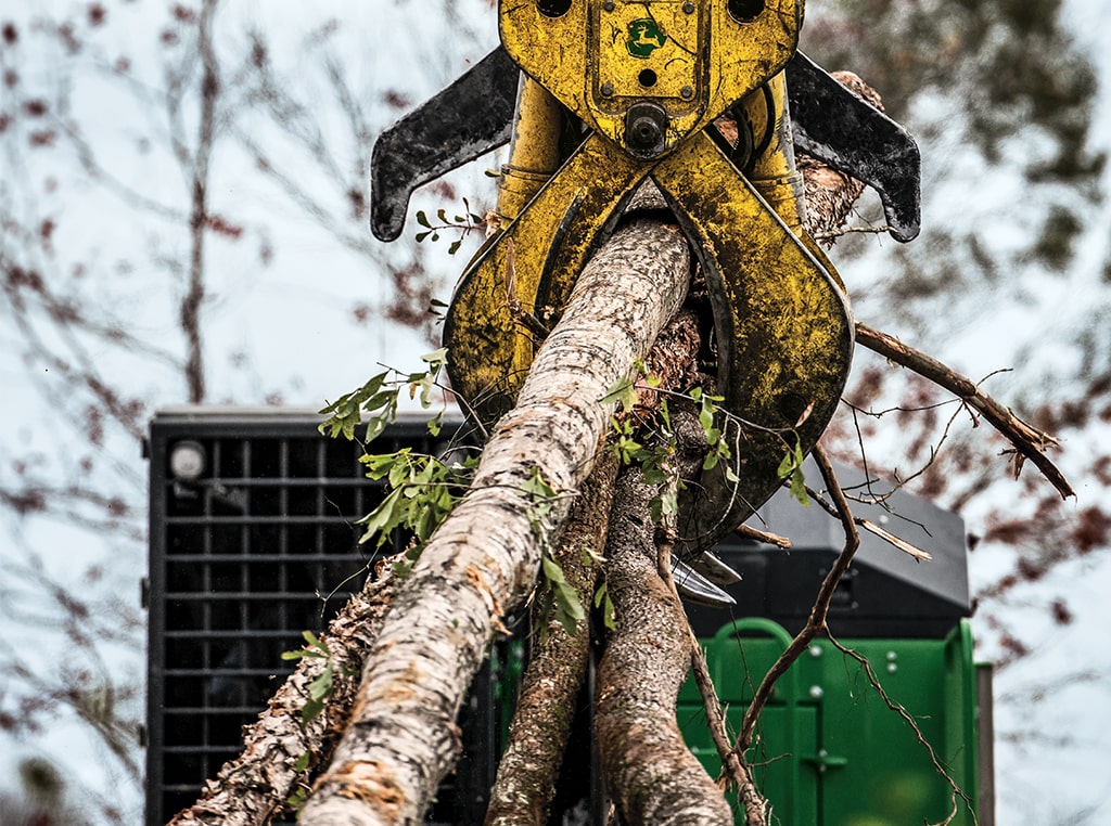A close-up of the 437E Knuckleboom Loader’s grapple holds felled trees of various sizes.