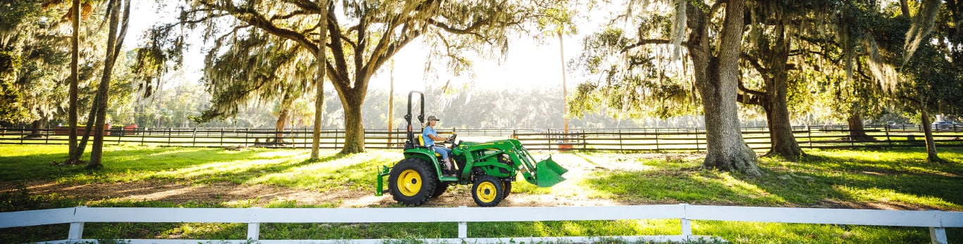 woman driving a tractor beyond a white fence