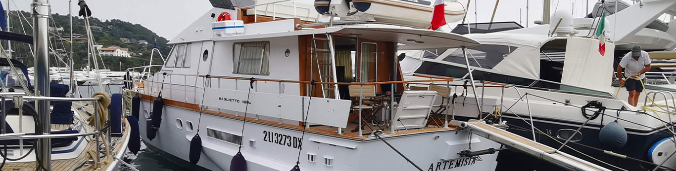 The Artemisia yacht docked on the water in Italy sitting between other boats