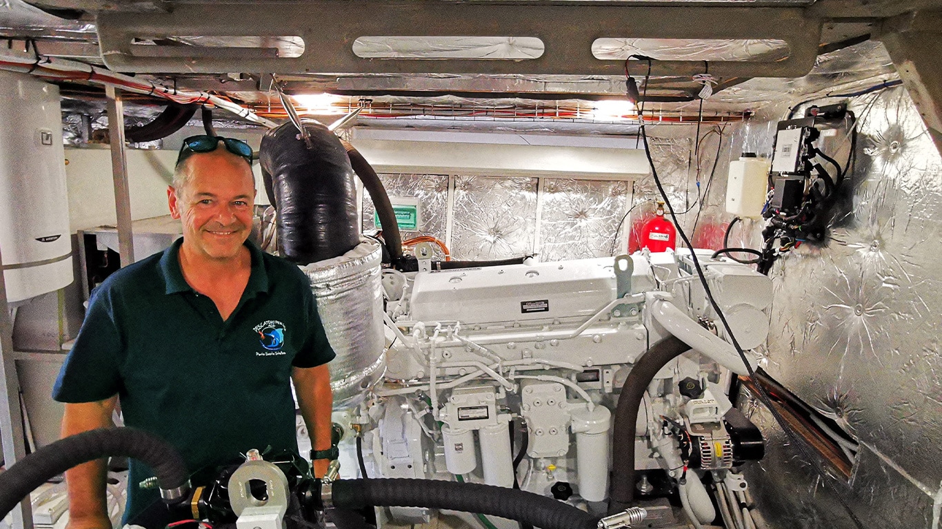 Marco Ambrogetti standing in the engine room of Artemisia in front of a John Deere marine engine