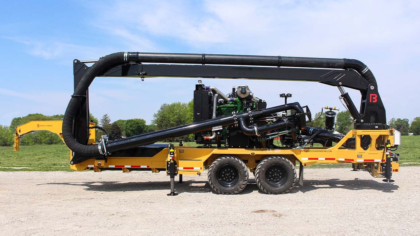 A side view of Bazooka Farmstar's Outlaw Boom Trailer manure pump on a farm.