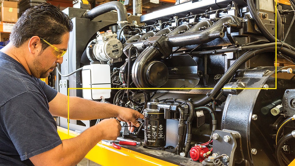 Tech works on an engine with three icons overlaying the image that represents connectivity, checklists and safety.