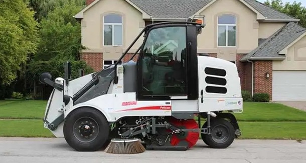Elgin Sweeper Pelican mechanical streetsweeper, powered by a John&nbsp;Deere 4.5L industrial engine, cleans a residential street. 