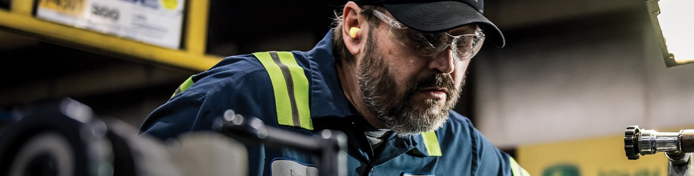 A John Deere technician working on a remanufactured engine