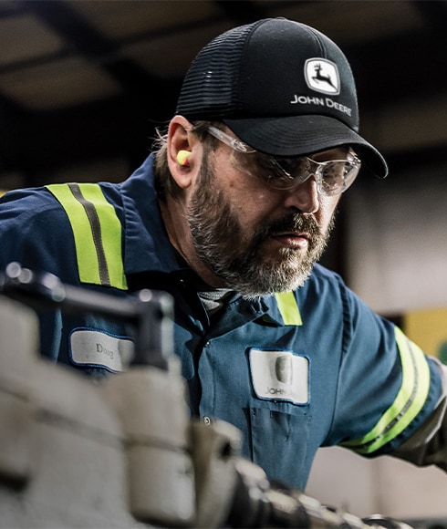 "A John Deere technician working on a remanufactured engine