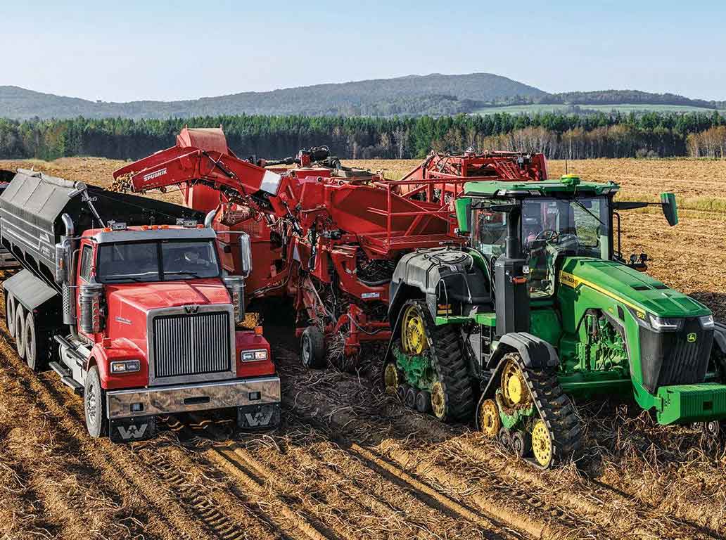 John Deere tractor and a Spudnik Equipment Co. 6631 3 Row AirSep Potato Harvester working in the field