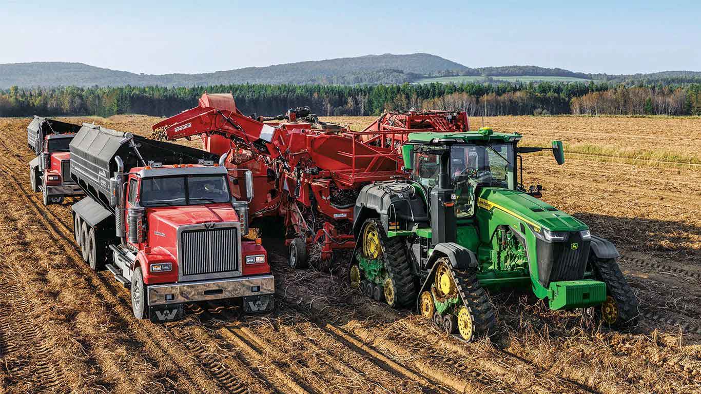 John Deere tractor and a Spudnik Equipment Co. 6631 3 Row AirSep Potato Harvester working in the field
