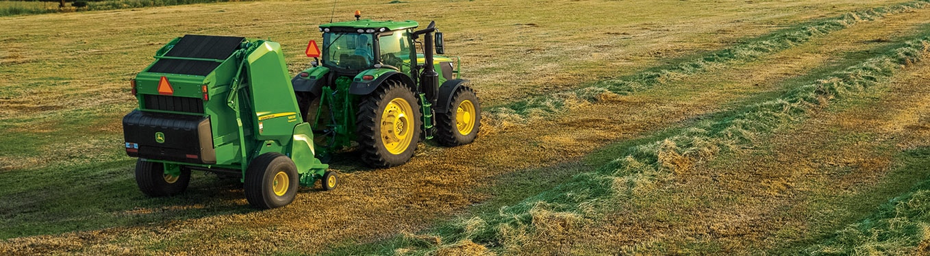 Tractor and round baler working in field.