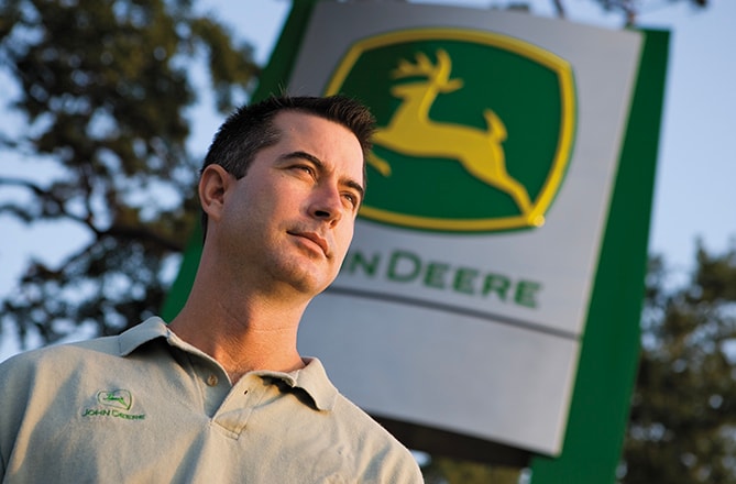 Dealer in front of John Deere sign. 