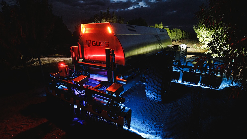 Nighttime view of sprayer in orchard.