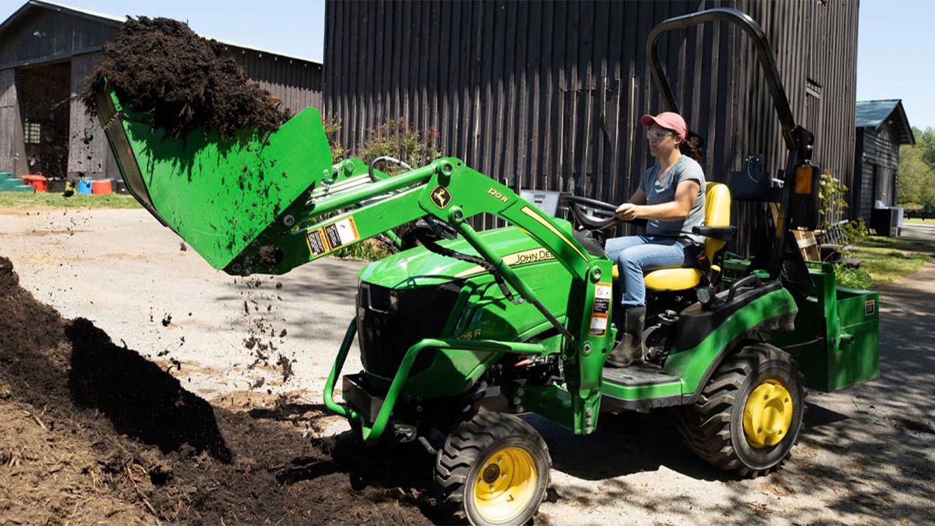 Woman scooping manure in a 1025r tractor