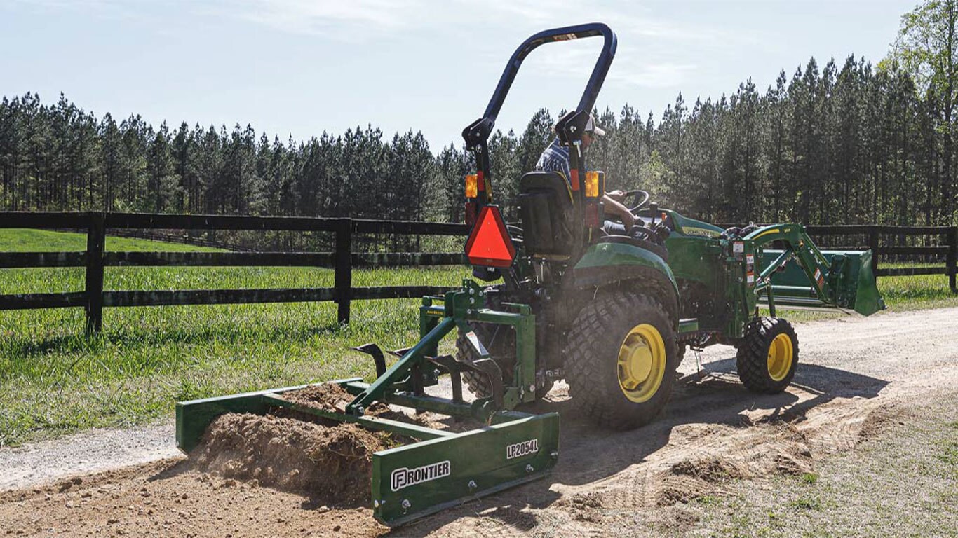  1025R with tilling attachment and shovel being used to till dirt for a path