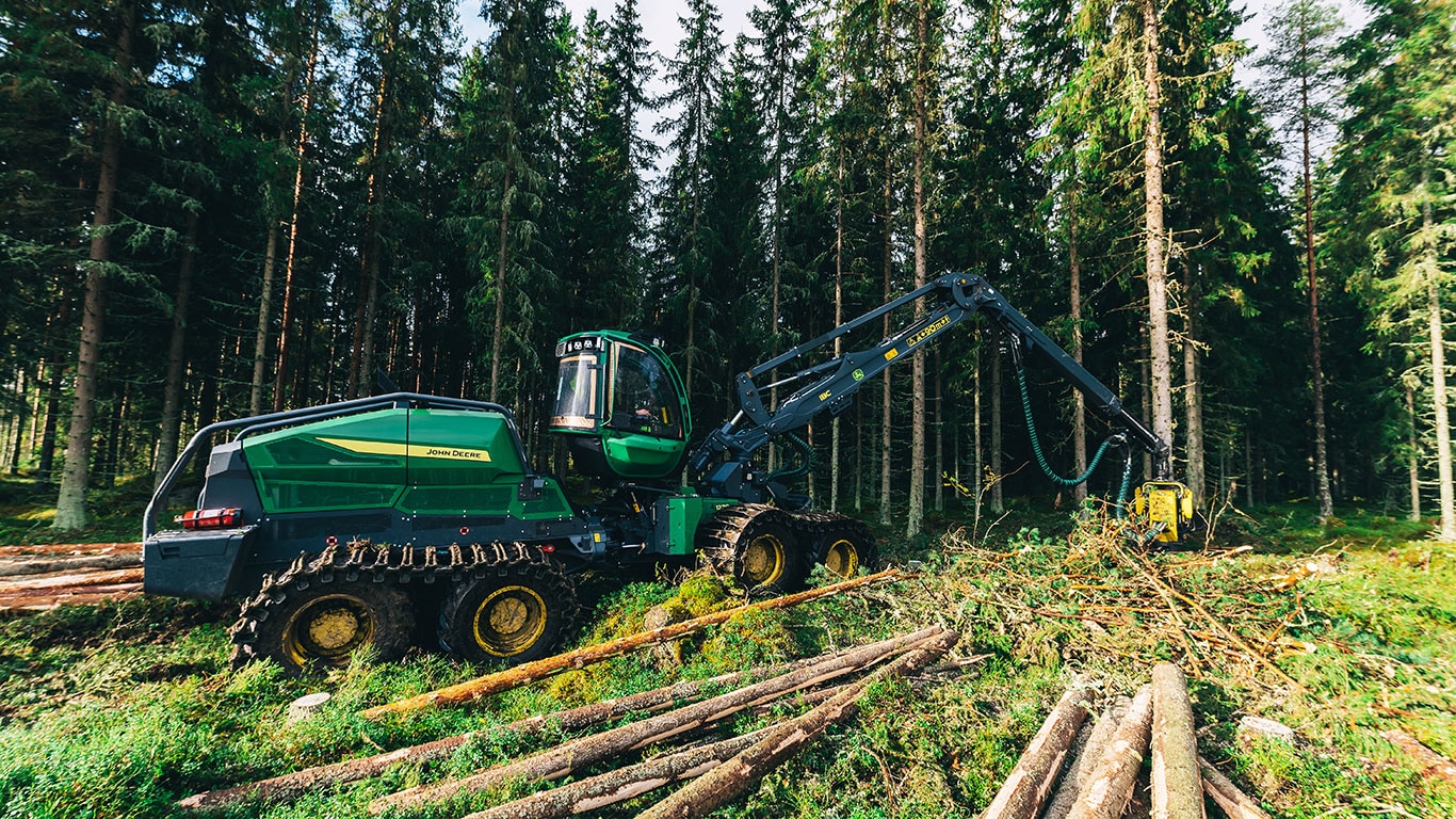 John Deere 1270H harvester operating in dense forest, cutting trees with precision arm.