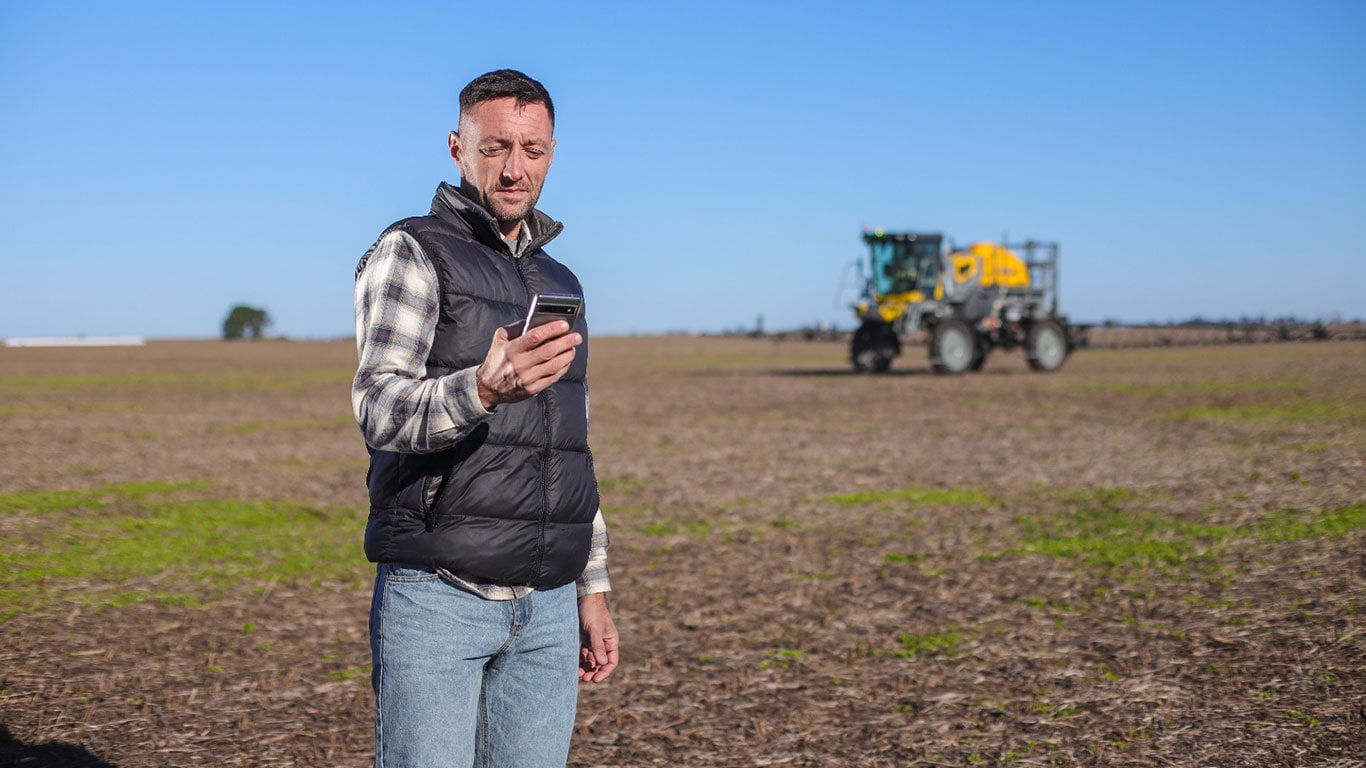 Un hombre en el campo, usando el teléfono celular.