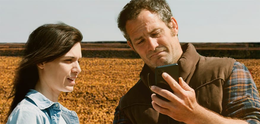 Un hombre y una mujer mirando un celular en el campo.