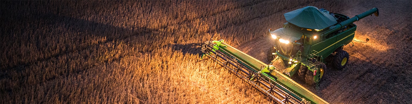 Cosechadora John Deere en el campo por la noche.