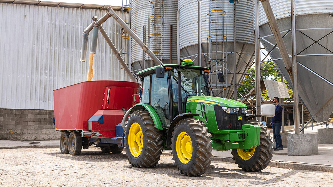 Tractor 5105M acoplado a una cargadora de grano.