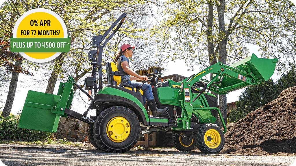 0% APR for 72 months, plus up to 1500 dollars off advertisement showing a woman in the seat of a John Deere 1 Series compact tractor loading dirt.