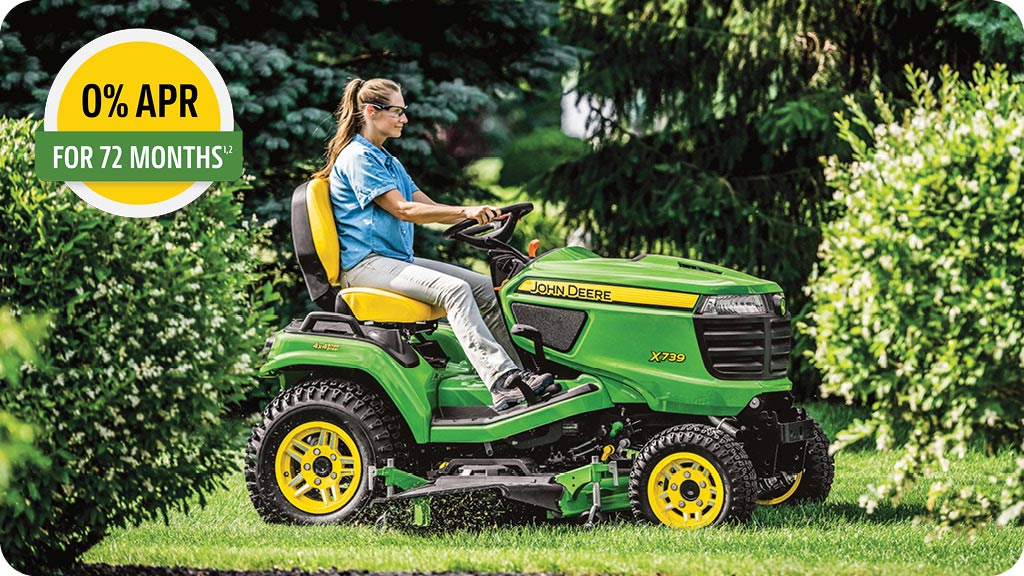 0% APR for 72 months advertisement showing a woman in the seat of a John Deere X739 riding lawn mower cutting grass.