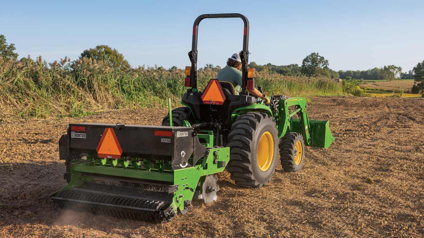John Deere Frontier implements attached to a tractor in a dirt field