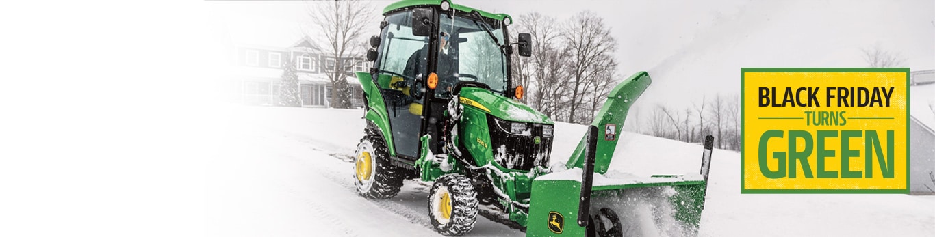 Person operating inside a 1025R Sub-Compact Tractor using a snow blower attachment