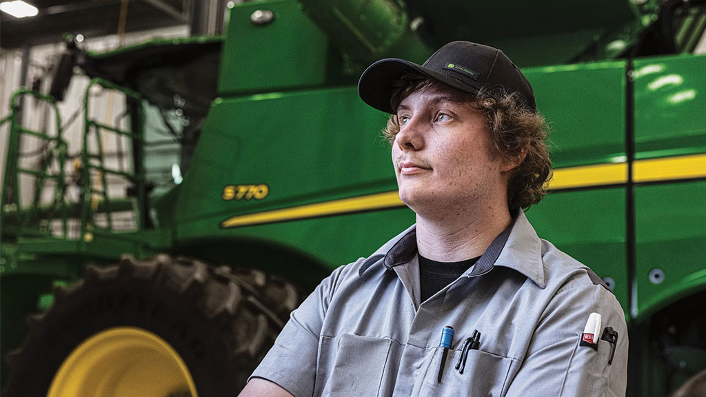 John Deere service technician in front of a combine