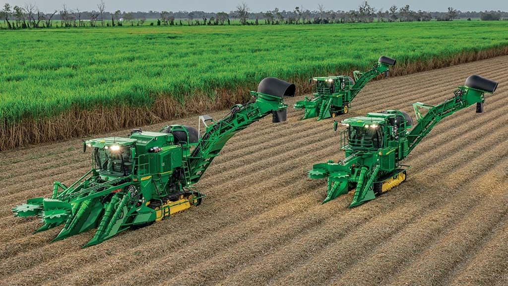 Wide-angle photo of three John Deere CH Series Sugar Harvesters at work in a sugar cane field.