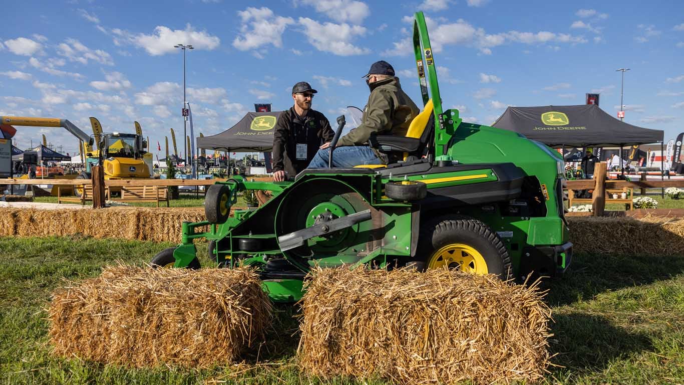 A large green 100-in. mower with the wingdeck folded up inside a hay course.