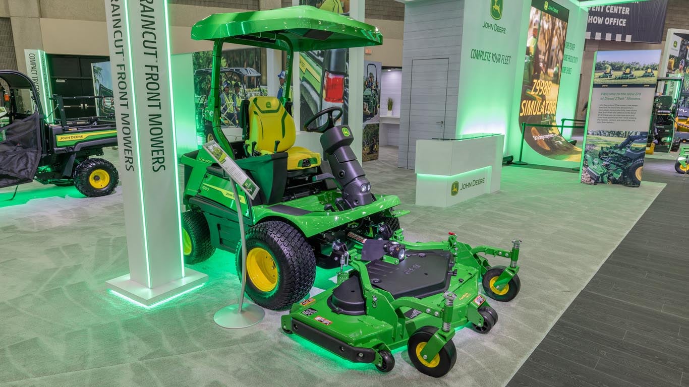 A green Terraincut front mower sits indoors next to a LED green sign.
