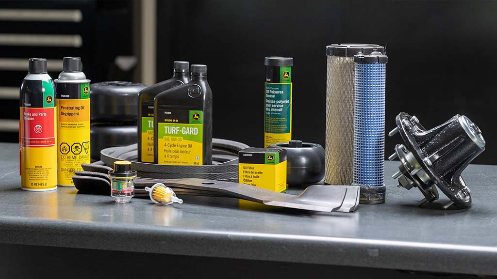 A table holding various oils, filters, mower blades, belts, and other equipment parts.