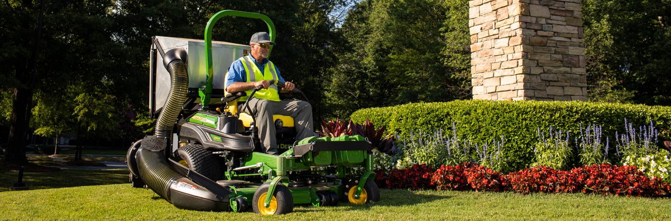 man mowing around a hedge with a commercial mower