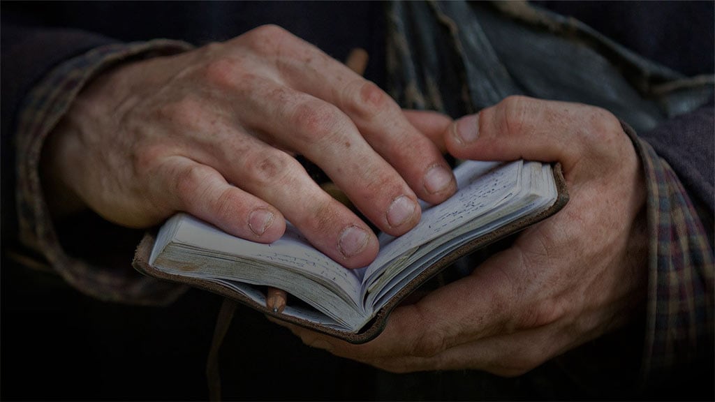 man's dirty hand holding a book