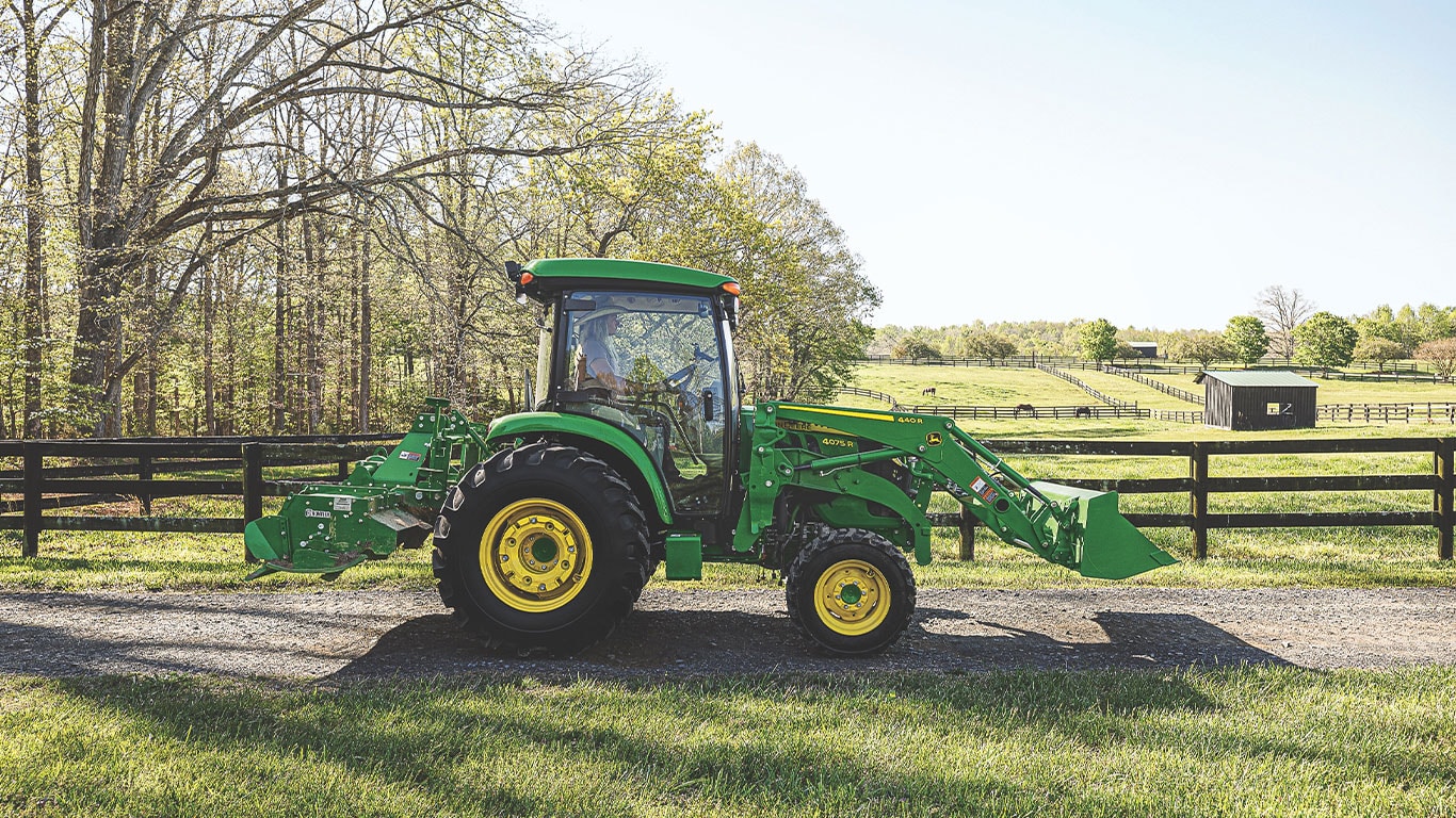 Photo of the 4075R on a farm in front of a pond on a gravel road 