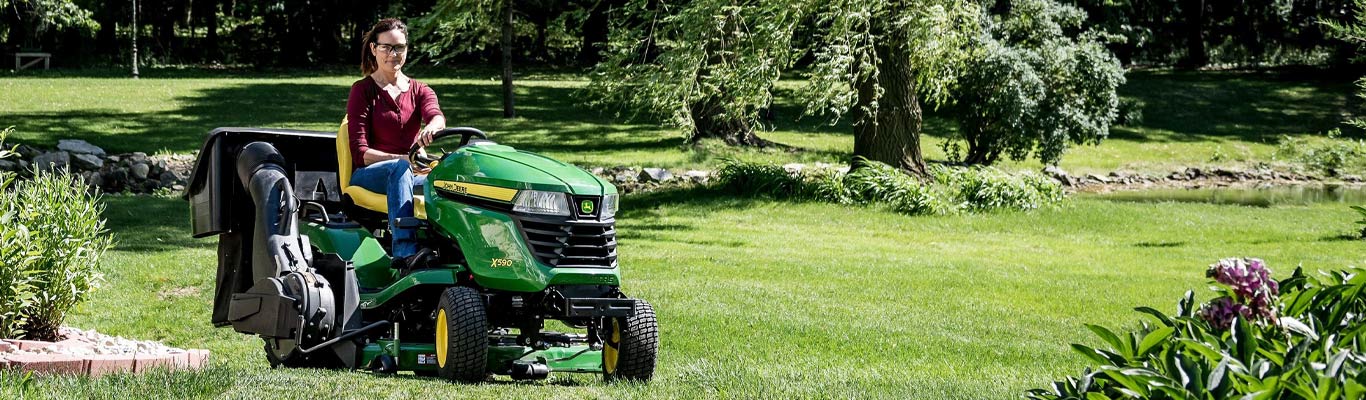 woman mows lawn on a John Deere riding mower