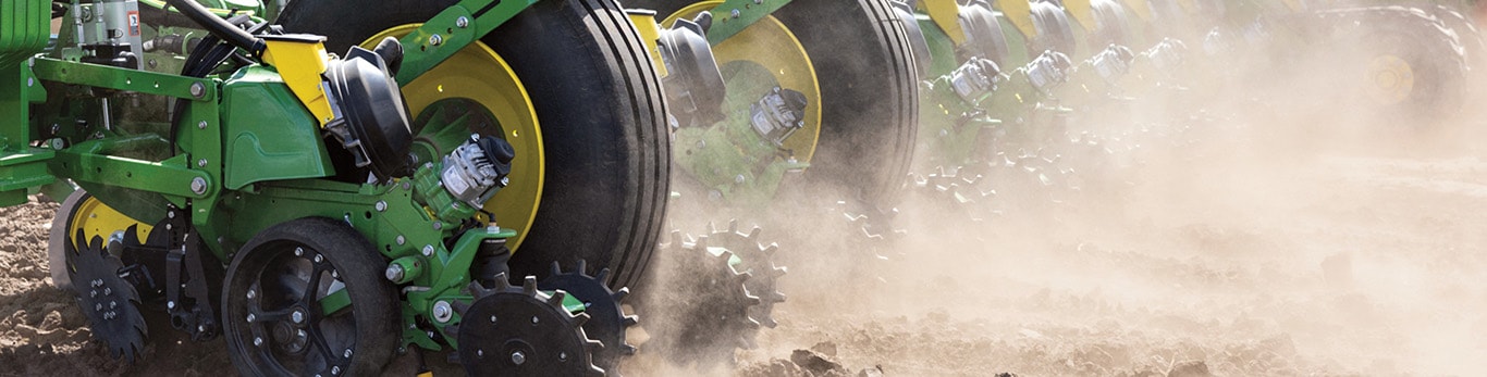 Close-up of planter row units kicking up dust as they move through a field.