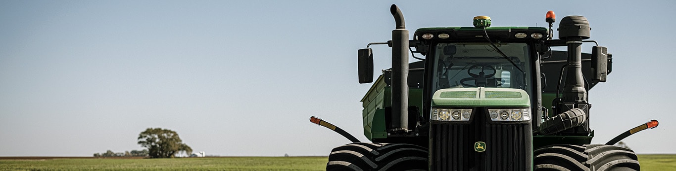 A large John Deere 4WD tractor parked in a field.