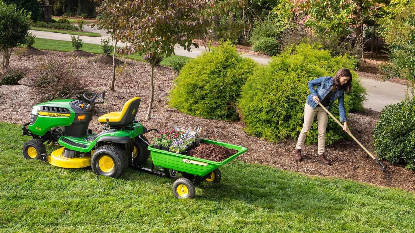 image of woman working in garden next to lawn tractor