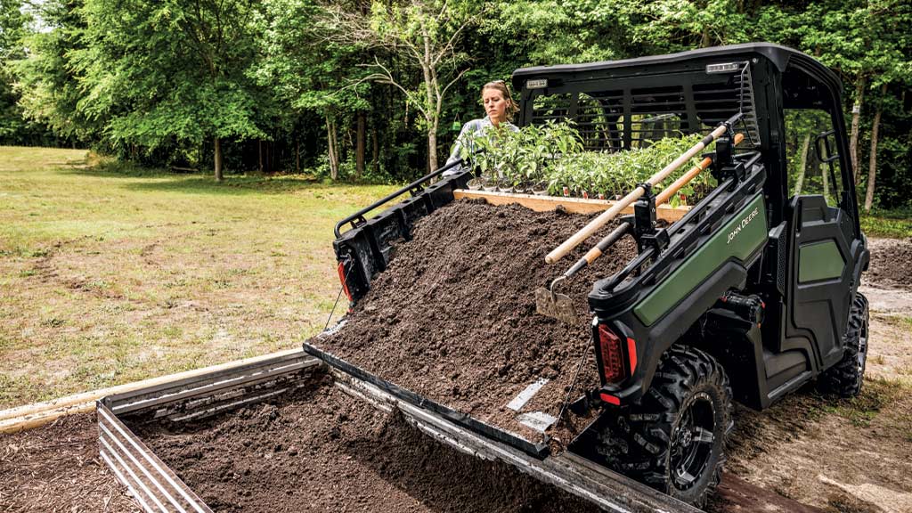 Person dumping dirt from the cargo box of a XUV 845M