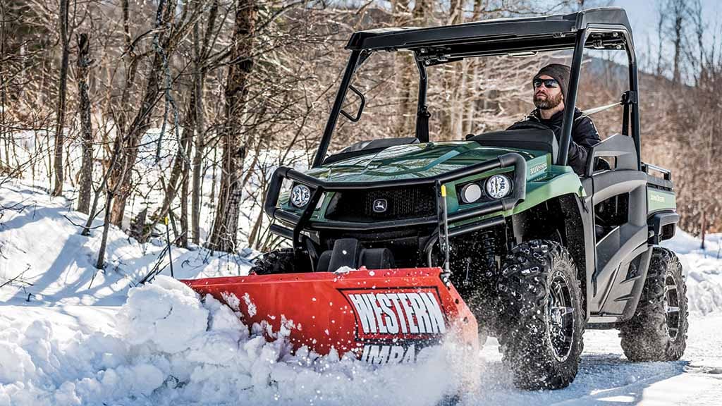 Person clearing snow with a Gator™utility vehicle equipped with a blade