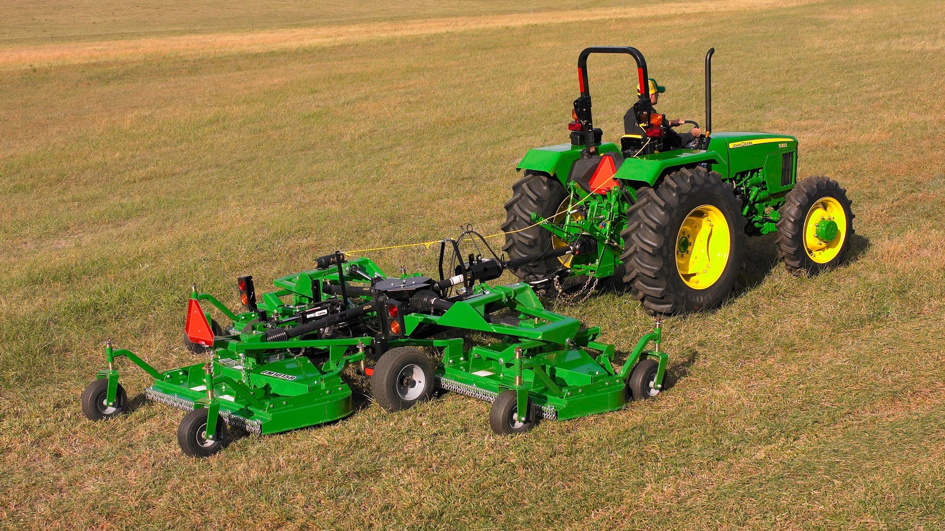 grooming mower attached to tractor in a field