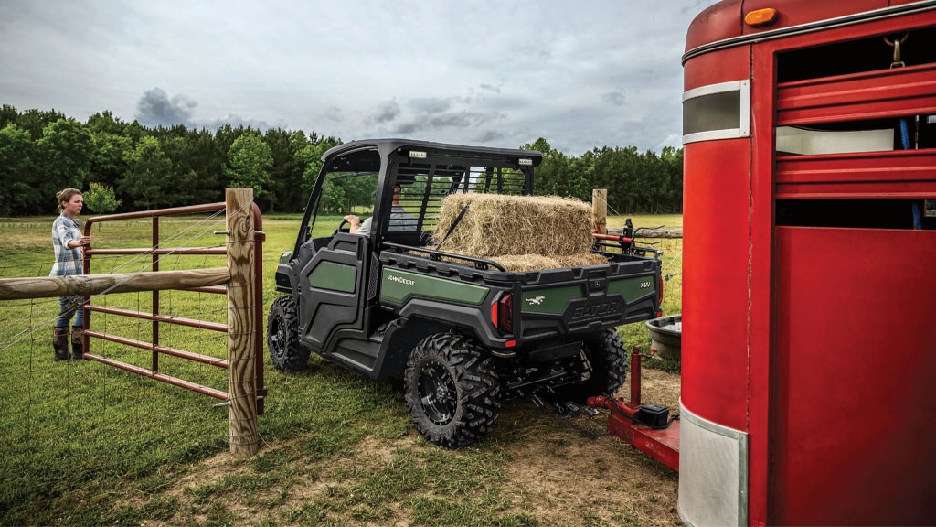XUV 845M pulling hay and cattle trailer through fence