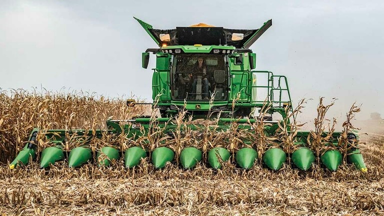 Frontal photo of a John Deere Combine with a partially unfolded CF12 Folding Corn Head
